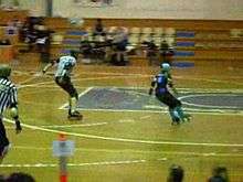 A roller skater circles the track while a referee points at her