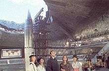 Large, underground missile silo with a missile pointing out the hole toward the sky next to a support structure. Five characters stand in the foreground.