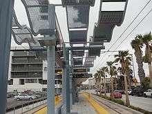 A train station at ground level with tracks on either side. The station is covered by wavy metal panels.