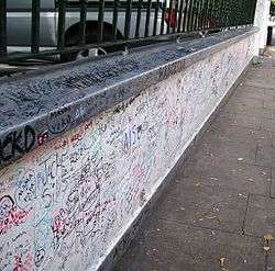 A grey topped white wall completely covered in handwritten messages