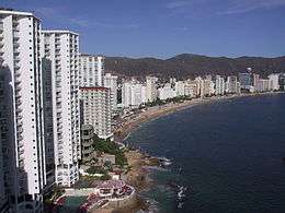 High view of the beachfront condos and hotels on the left, the long curved beach, Pacific Ocean on the right