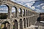 A three-storied aqueduct running through a town.