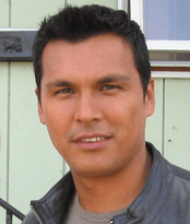 "A colour bust photo of Adam Ruebin Beach wearing a grey leather bomber jacket."