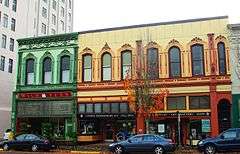 Photograph of a two-story, multicolored commercial building on an urban street