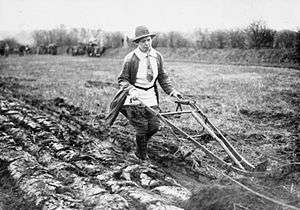 Members of the Women's Land Army operates a single-furrow plough on a British farm in 1914.