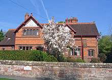 A red-brick house with two gables, one larger than the other