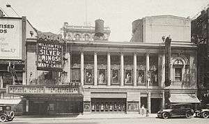 Theater building facade with colonnade spanning second and third stories and marquee and entrance on the left for two theaters.