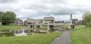 A photo looking East towards the Apollo Pavilion from a footpath which runs beside the lake that runs through the Pavilion, The sky is overcast and filled with clouds.