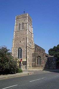 A tall flint tower with the body of the church extending beyond it