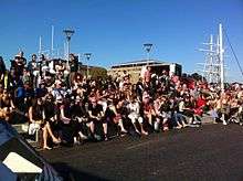 People on steps on a sunny day watching something