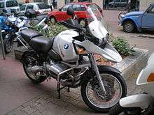 Silver BMW R1150GS parked on a city street with other cars and bikes in the background