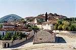 White houses with greyish roofs on a hillside.