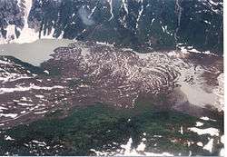 Brown rock lying in a glaciated valley with a small lake on the left.