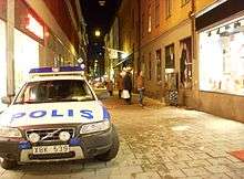 Narrow street, with pedestrians and a parked police car