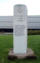 An austere, plain pillar with an emblem and an inscription on it