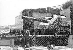 Soldiers standing in front of a gun housed in a casemate