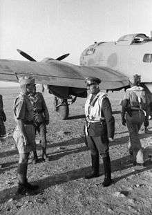 a black and white photograph of a male in uniform standing alongside an aircraft