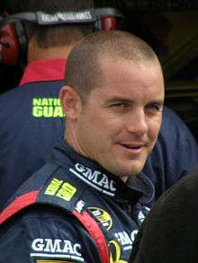 Semi-profile of a man in his late-twenties, clean shaven and smiling.