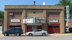 Two-story brick building; triangular marquee projecting from front; vertical "State" sign projecting from corner