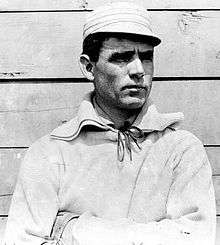 Clark Griffith standing against a wall and looking right, wearing a baseball uniform