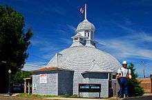 Photograph of a domed wooden building with a statue of a lumberjack in front