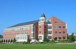 An exterior shot of a red brick building with a dark roof and white window frames.