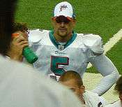 Man in football uniform with hands on hips on football field sideline