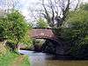 The bridge spans the canal with a footpath on the left and trees on each flank.