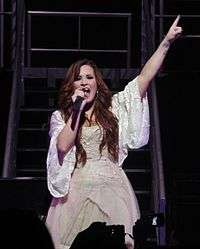 A smiling woman in front of a microphone stand.