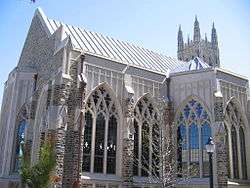 Cathedral-sized arched and intricate windows on chapel are displayed prominently in foreground with larger soaring chapel peaking out at the top