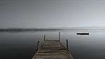 A dock extends from the shore of an extremely wide river.