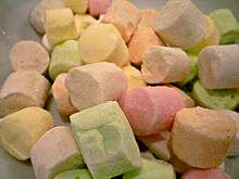 A pile of small cylindrical pieces of confectionery each one a different pale pastel colour