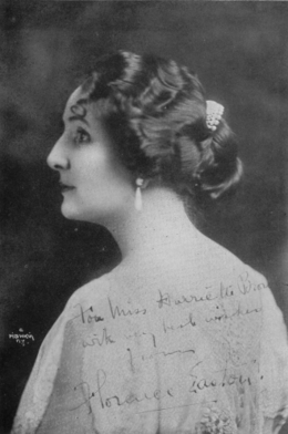 Head and shoulders rear-view studio portrait of an elegant lady in her thirties looking to her left. She is wearing a simple dress but has an elaborate hair-style with jewellery. The portrait has been partially over-written with a greeting and signature by the sitter.