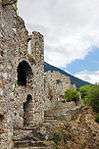 A complex of buildings partially in ruins in a mountain landscape.