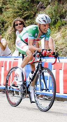  A man riding a bike while wearing a green uniform.