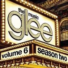 Close-up of a multi-storey traditional theatre marquee with chasing lights. The word "Glee" in spelled in lights, with the words "The Music" printed above. all in minuscule. The words "Volume 6" and "Season Two" are printed in lowercase black font on the heading of the marquee.