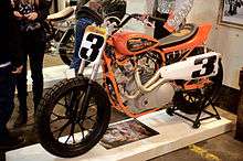 Left-side view of an orange and white racing motorcycle taken at The One Motorcycle Show in Portland, Oregon