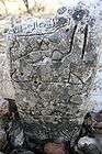 Close up view of the inscription of a rock that does not seem to have been worked on by a stonemason, given its irregular shape and unsmoothed surface.