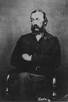 b&w seated portrait photo of a bearded man