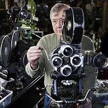 Martin Hill stands behind an old movie camera