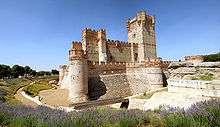 A stone castle, surrounded by an empty moat.