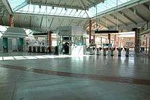 An empty entrance of a train station with many ticket machines located in a distance