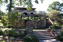 Several tiers of steps descend from a two-story stone building with arched open entrances.