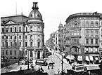 A black and white photograph of 1892 of a city street crossing, with 2 rows of houses.