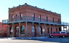 Photograph of a two-story, brick commercial building on a street corner.