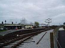 Curving concrete station platform. There is a small wooden hut on the platform.