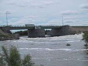 A concrete and metal structure spans a section of choppy water