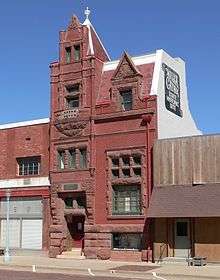 Narrow four-story brick building with extensive stonework around doors and windows; "Willa Cather State Historic Site" painted on side