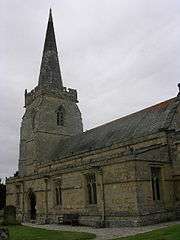 Part of a stone church seen from the southeast, with a protruding south aisle, and a tower surmounted by a spire