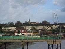  Beyond a river pier white cliffs rise up with a church and steeple on the skyline